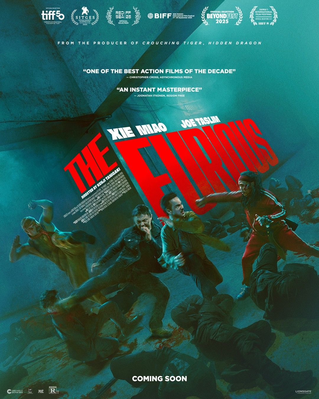Teal-tinted action movie poster with a large red diagonal title and a group of people running, critics’ quotes at the top, and 'COMING SOON' at the bottom.